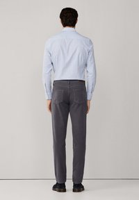 Pantalones grises de corte slim, acompañados de una camisa a rayas azul claro. Los pantalones tienen bolsillos traseros y una textura suave.