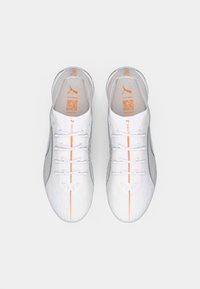 Baskets de sport blanches avec une tige texturée, des accents gris clair, des détails orange le long des lacets et une forme élancée et aérodynamique.