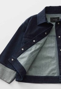 Giacca in denim scuro con colletto strutturato, bottoni a pressione argento e foderatura in tessuto più chiaro. Presenta cuciture in contrasto e una tasca.