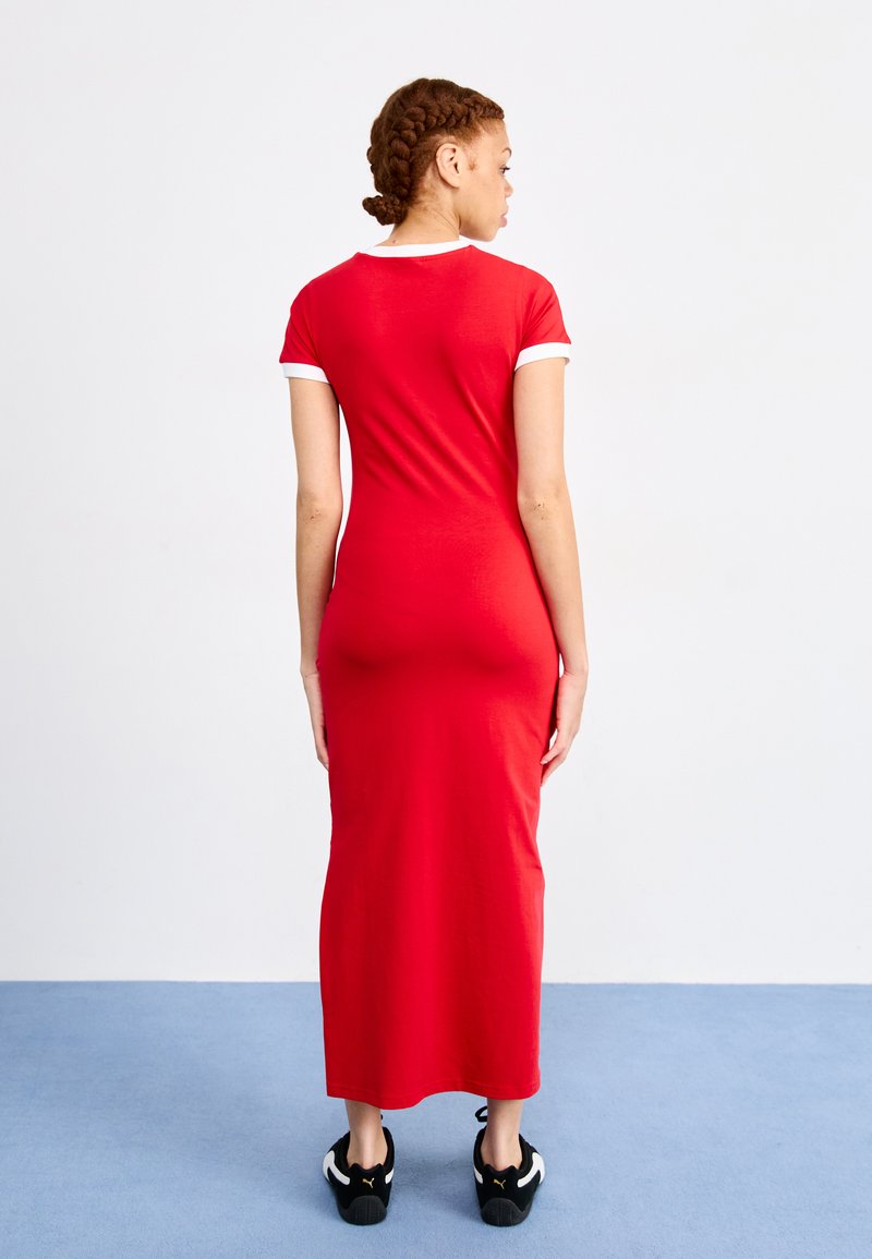 Maxi vestido de algodón rojo con mangas cortas blancas, silueta ajustada, longitud a mitad de pantorrilla, y combinado con zapatillas negras.