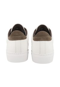 Un paio di sneakers bianche con inserti in suede marrone sul tallone, viste da dietro su uno sfondo bianco.