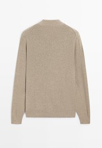 Beżowy sweter z długim rękawem o prążkowanej fakturze. Posiada okrągły dekolt i prosty krój, wykonany z miękkiego dzianinowego materiału.