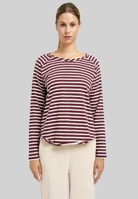 Langarmshirt mit kastanienbraunen und cremefarbenen Streifen, rundem Halsausschnitt, lässiger Passform und weichem Stoff. Kombiniert mit beigen, gerippten Hosen.