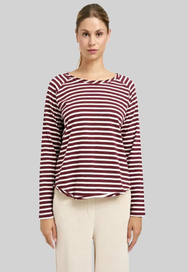 Langarmshirt mit kastanienbraunen und cremefarbenen Streifen, rundem Halsausschnitt, lässiger Passform und weichem Stoff. Kombiniert mit beigen, gerippten Hosen.