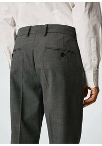 Kalhoty s šedým kostkovaným vzorem a slim fit střihem, které mají dvě zadní kapsy s knoflíkovým zapínáním a hladkou texturu látky.
