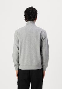 Grauer Pullover mit hohem Kragen, gerippten Bündchen und Saum. Hergestellt aus weichem Stoff, mit glatter Textur und schlichtem Design.