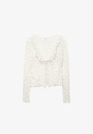 Witte langwerpige blouse met lange mouwen, met een gestructureerd patroon en ruffles rond de halslijn, en een striksluiting aan de voorkant.