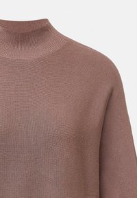Ripp Pullover-Pullover in einem sanften Mauve-Ton, mit hohem Kragen und glatter Textur. Der Stoff wirkt leicht und dehnbar.