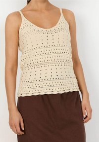 Lichtbeige gebreide tanktop met v-hals, met open steekpatronen en gegolfde randen, gecombineerd met een bruine rok.