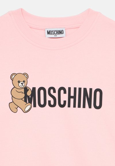 Sudadera de algodón rosa con un gráfico de oso de dibujos animados y el texto "MOSCHINO" en negro. Cuello de canalé y textura suave.