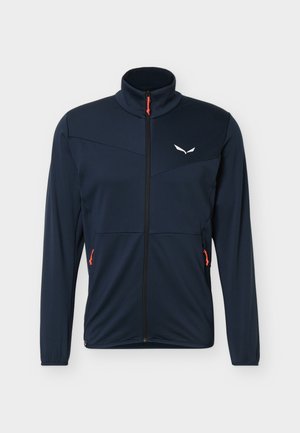 Marineblauwe jas met ritssluiting, hoge kraag, lange mouwen, wit logo op de borst en oranje ritsuiteinden aan de zakken tegen een witte achtergrond.