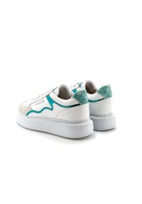 Zapatillas blancas con acentos turquesa, con puntera de ante y talón texturizado. Presentan una suela blanca gruesa y detalles cosidos a lo largo del upper.