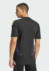 Zwarte sporttrui met verticale strepen, korte mouwen en limoen groene accenten. Bevat paarse zijdetails en een standaardkraag.