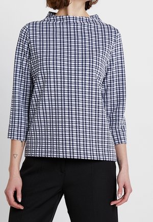 Blau-weiße karierte Bluse mit hohem Kragen und Dreiviertelärmeln, aus strukturiertem Stoff. Schlichtes Design und lockere Passform.