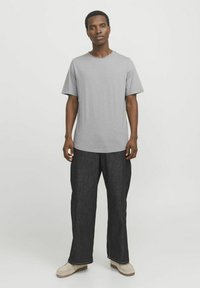 Graues Kurzarm-T-Shirt mit rundem Ausschnitt, kombiniert mit dunkelblauen, weiten Jeanshosen und hellen Schuhen. Einfaches und lässiges Design.