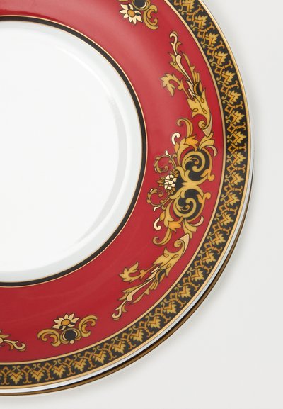 Assiette en porcelaine blanche avec un large bord rouge orné de motifs floraux et volutes complexes en or et noir.
