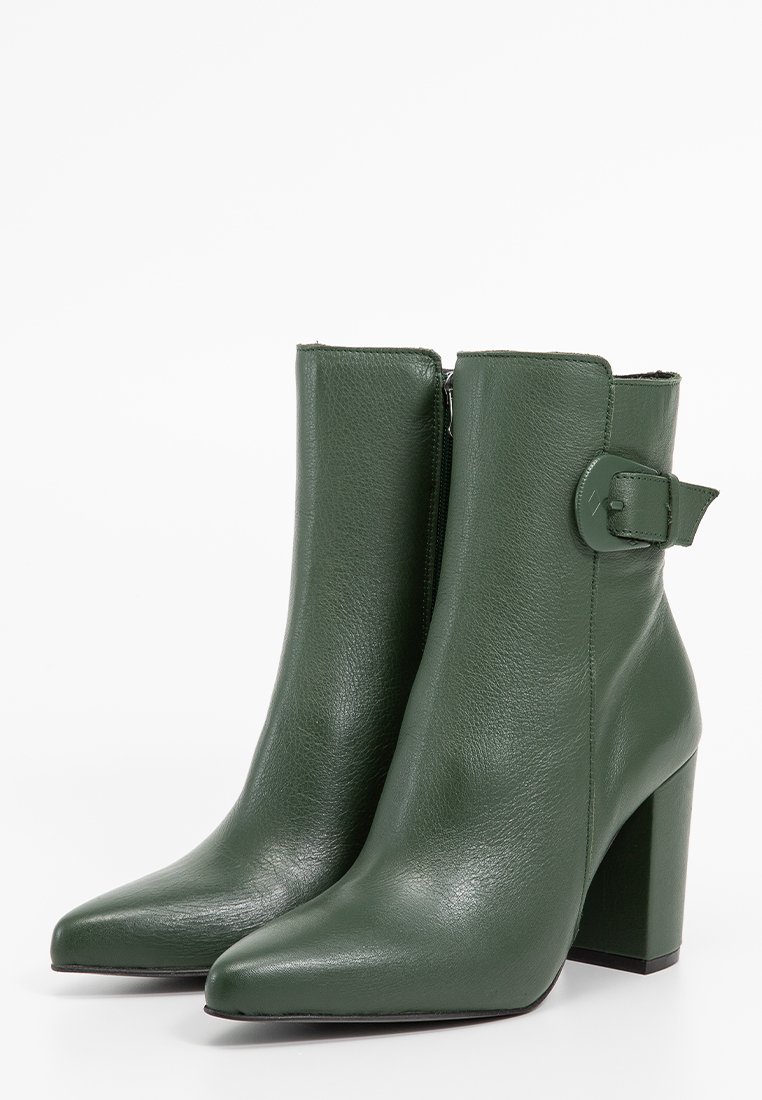 Zielone skórzane botki za kostkę z wąskim noskiem, słupkowym obcasem i akcentem w postaci klamry z boku. Gładka tekstura z wysokim połyskiem.