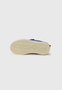 Baskets bleues avec une tige légère, une semelle en caoutchouc présentant un motif de relief, et un accent beige contrastant au niveau du talon.