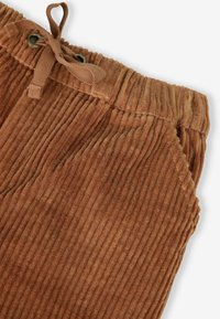 Braune Cordhosen mit vertikaler Ripptextur, ausgestattet mit einem Kordelzugbund und seitlichen Taschen. Der Stoff wirkt weich und samtig.