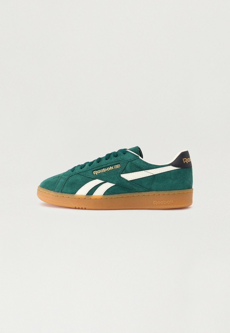 Baskets Reebok en daim vert avec bandes blanches et semelle en gomme, vues de profil sur un fond clair uni.