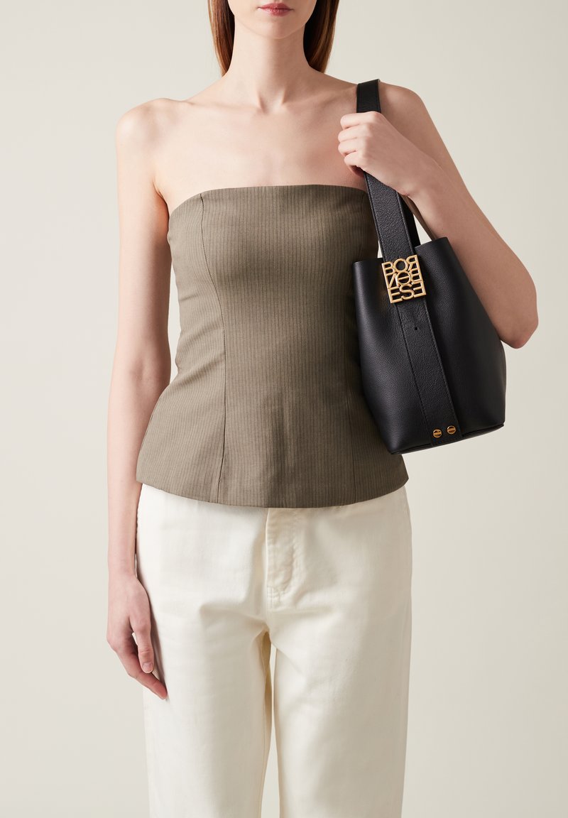 Olive ribbed strapless top with a fitted design, paired with cream wide-leg pants and a structured black leather bag featuring a gold logo accent.