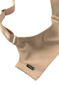 Beige justerbar stofsele med metalspænde og sort "Closely" mærkat syet nær kanten.