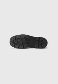 Sort gummisål med dybe dækmønstre og hexagonale studs, størrelse 41, isoleret på en ensfarvet baggrund.