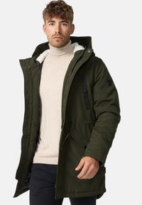Olive green parka jacket with a removable hood, fleece lining, and snap-button and zip closures. Features two front pockets and diagonal accents.