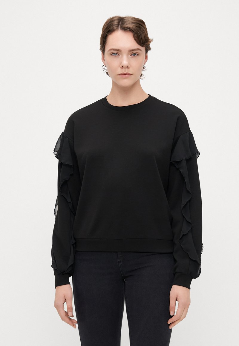 Sweatshirt preto com mangas longas e detalhes em camadas de babados. Tecido macio e decote redondo com uma cintura ajustada.