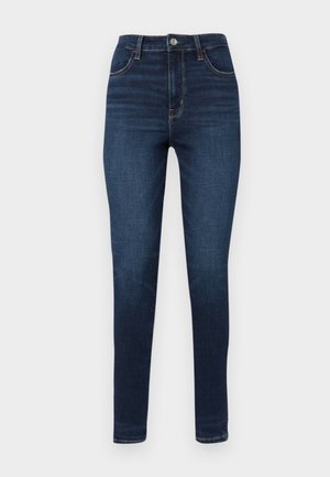 Mørkeblå høyde jeans med en tettsittende silhuett, fem lommer og kontrasterende oransje sømdetalj langs sømmene.