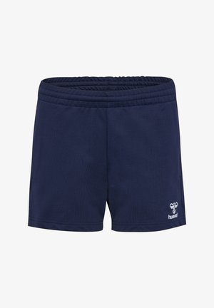 Enfant portant un short bleu marine, des chaussettes blanches et des baskets blanches avec des chevrons noirs sur un fond uni.
