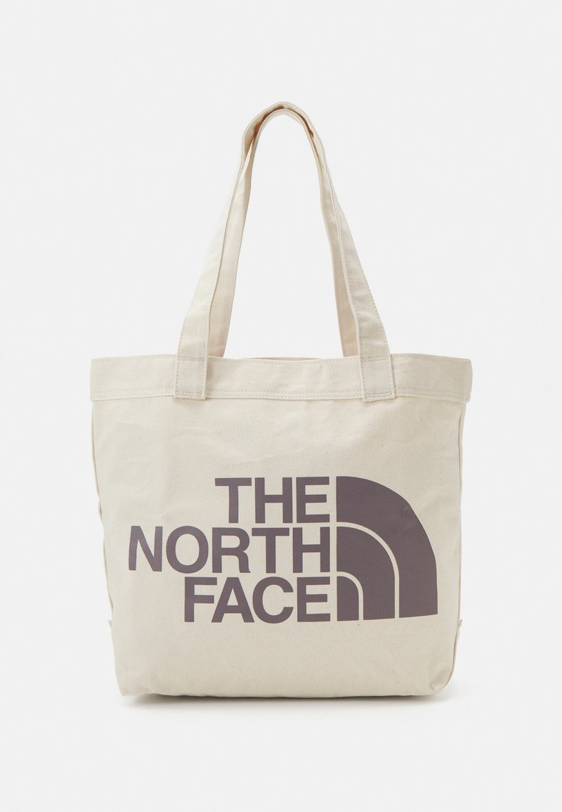 Bolso tote de lona beige con dos asas resistentes y un gran logo de marca gris oscuro en la parte frontal. Diseño simple y rectangular.