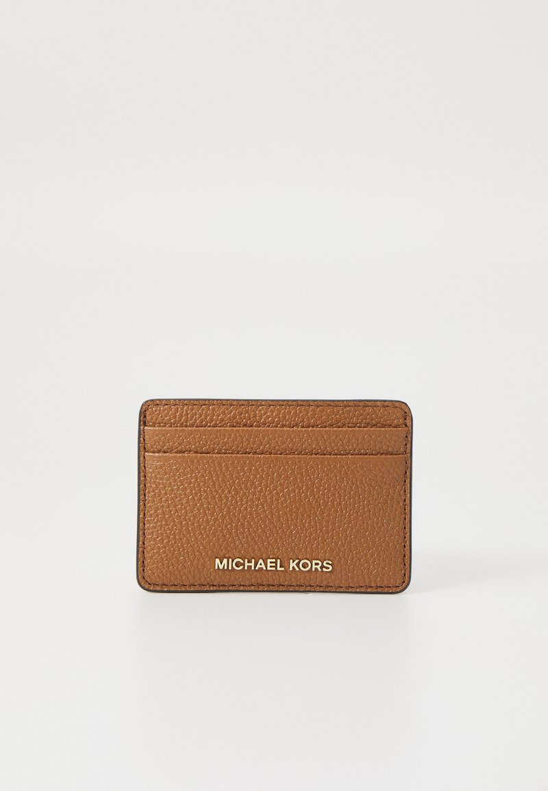 Rudas odinės kortelių laikiklis su tekstūruotu paviršiumi, keturi kortelių laikymo skyreliai ir įspaustas "MICHAEL KORS" logotipas auksinės spalvos. Minimalistinis dizainas.