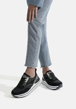 Sneaker nere e verdi con un design low-top, materiali in camoscio e tela, dettagli testurizzati e una suola stratificata bianca.