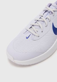 Baskets de sport violettes claires avec une tige en maille, des accents blancs et un logo swoosh bleu. Caractéristiques : lacets plats et semelle texturée.
