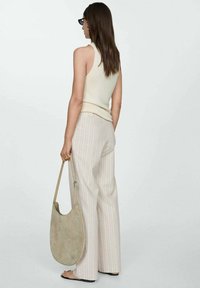 Débardeur beige à côtes, pantalon large rayé clair, et sac à épaule vert tendre. Fond uni, mise au point sur les vêtements et les accessoires.
