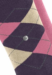 Calzino con motivo argyle colorato, caratterizzato da diamanti rosa, beige e navy, con una decorazione verde e un'etichetta metallica.