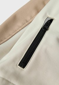 Reißverschlusstasche aus beige- und hellcremefarbener Stoff, ausgestattet mit einem schwarzen Reißverschluss. Glatte Textur mit kontrastierenden Farbflächen und sauberem Nähen.