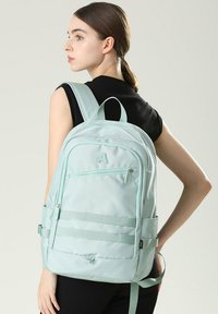 Aqua groene stoffen rugzak met dubbele ritssluitingen, verstelbare schouderbanden, zijzakken en horizontale webbingaccenten.