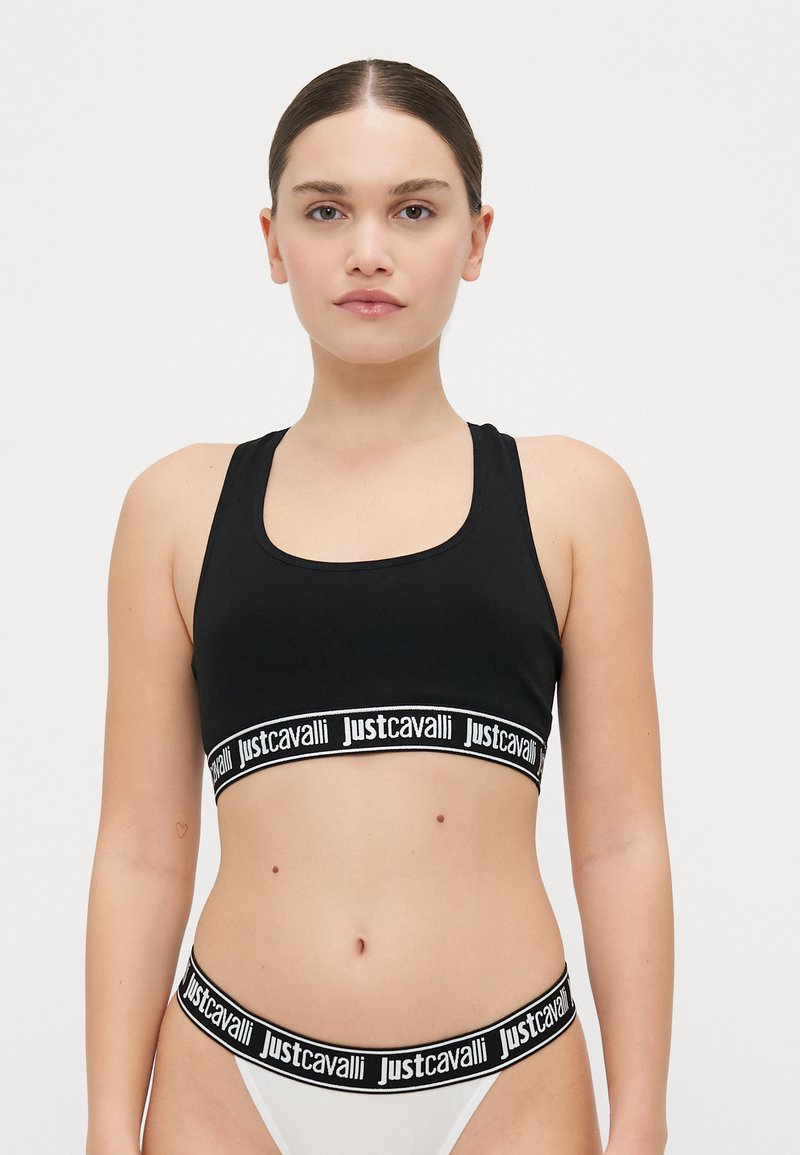 Soutien-gorge de sport noir avec large bande élastique portant le logo "justcavalli" en blanc. Texture lisse, décolleté en scoop et design dos nageur.