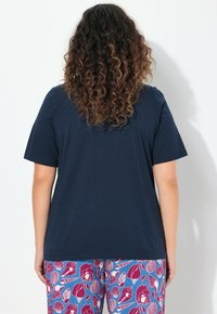 T-shirt a maniche corte blu navy con una vestibilità rilassata. Abbinato a pantaloni rosa con motivi di conchiglie e gelati.