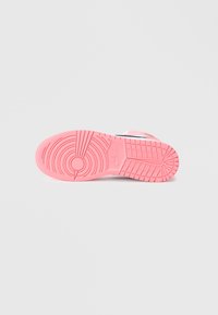 Buty Nike z różową gumową podeszwą zewnętrzną, posiadające okrągły wzór bieżnika i wyraźne logo. Design jest prosty i sportowy.