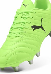 Sjajno neonsko zelene kopačke s teksturiranim gornjim dijelom, tonovima pruga i crnim Puma logom. Ima metalne krampe za prianjanje.