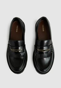 Sorte læder loafers med en blank finish, frynset design og gylden detalje fortil. Rund tå og tekstureret sål.