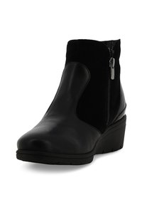 Stivaletto nero con pelle liscia e pannelli in suede morbido, dotato di cerniera laterale e tacco a zeppa. Punta arrotondata e suola texturizzata.