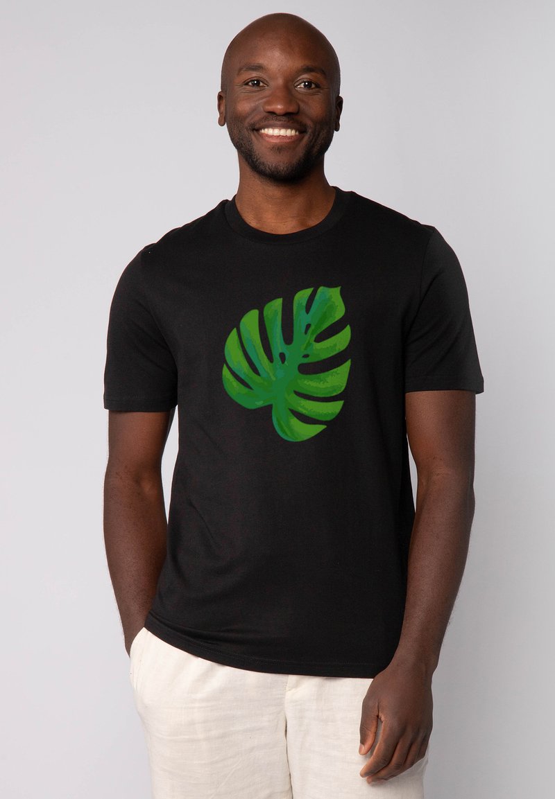 Schwarzes T-Shirt mit kurzen Ärmeln, das auf der Vorderseite ein großes grünes Monstera-Blatt-Design zeigt. Das Material sieht weich und glatt aus.