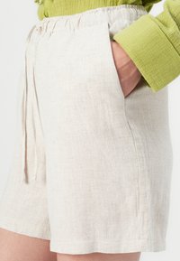 Linnen shorts in een lichte beige kleur met een gestructureerde oppervlakte, voorzien van zijzakken en een trekkoord in de taille.
