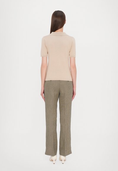Polo shirt beige a maniche corte abbinato a pantaloni a quadri verde oliva, con una gamba dritta e texture a contrasto.