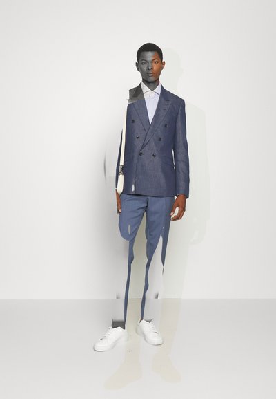 Kék vászon, dupla gombos zakó fekete gombokkal, világos csíkos inggel és fehér sportcipővel párosítva. Sima textúra, illeszkedő dizájn.