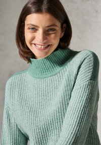 Miętowa dzianinowa bluzka z wysokim prążkowanym kołnierzem, z teksturowanym wzorem i dopasowanym krojem.